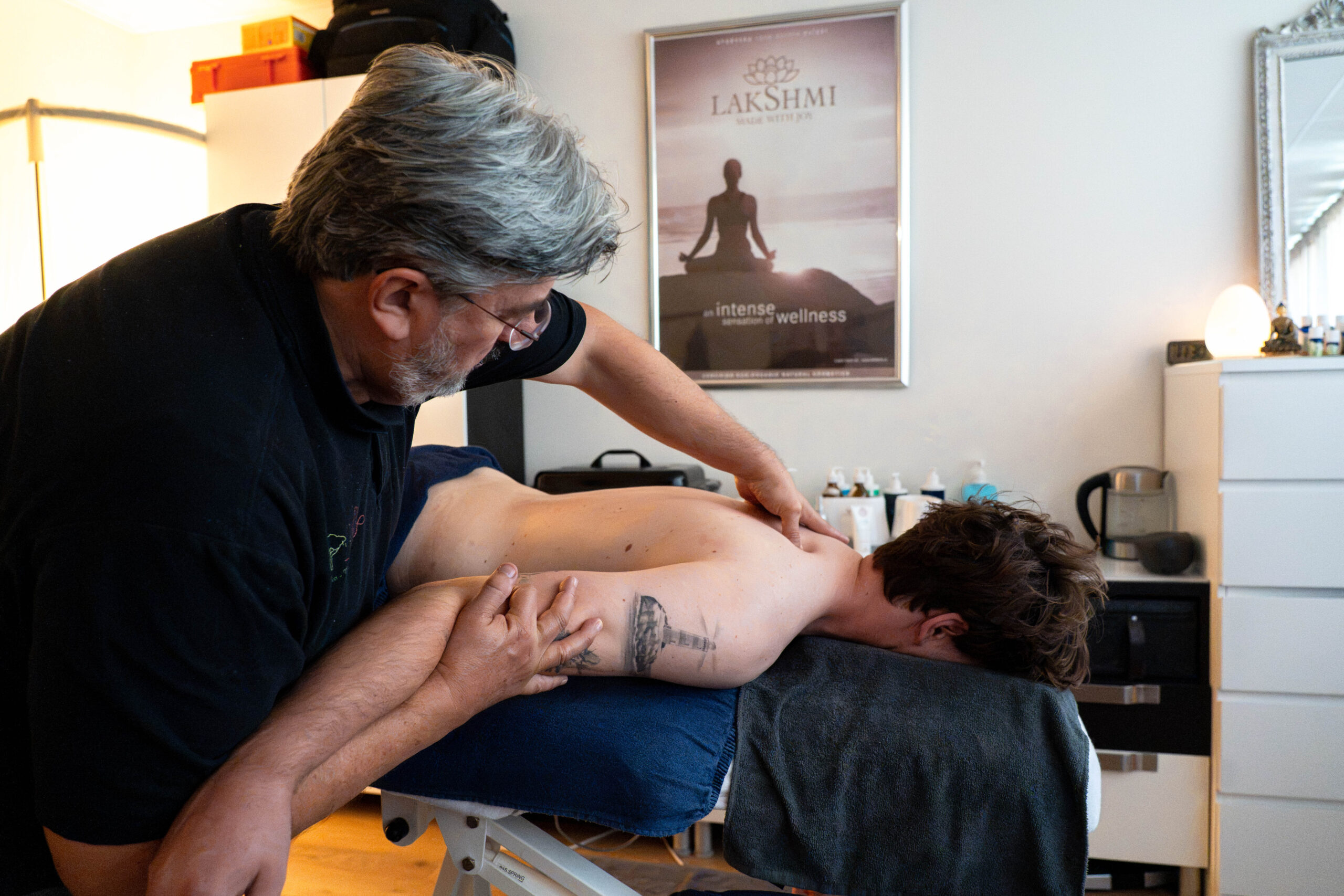 Moreno Giraldi behandelt de schouder en bovenrug van een cliënt op de massagetafel.